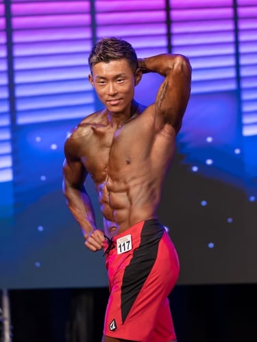 Sho competing on stage in his first physique competition after 32 week transformation