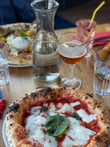 Pizza margherita napolitaine servie à table avec basilic frais au restaurant Histoire sans Faim à Lausanne, ambiance