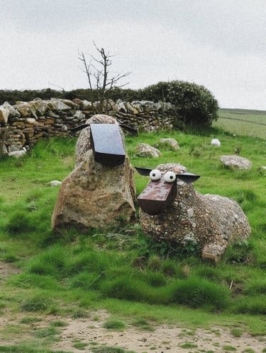 Rustic stone sheep sculptures in a grassy garden field, adding character, texture and natural charm