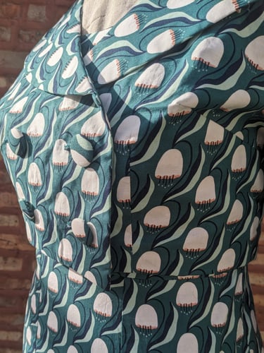 The front of a green art nouveau reversible sheath dress and 50's inspired cropped jacket