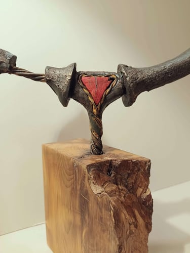 Close up of a semi circular, linear sculpture, painted bronze with red detail, on yew plinth.