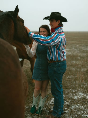 a man and woman standing in a field with horses