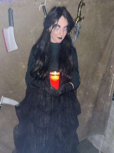 a woman in a black dress holding a candle