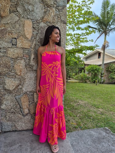 Mulher em pé usando um vestido com babado franzido, estampado nas cores rosa e laranja