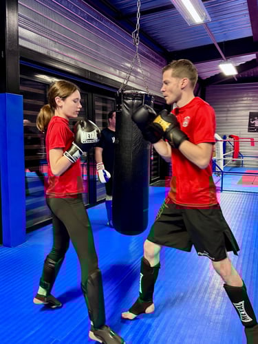 Entraînement de boxe : un homme et une jeune fille en garde, prêts à boxer