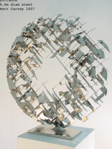 a silver cross-hatched circle sculpture  side view