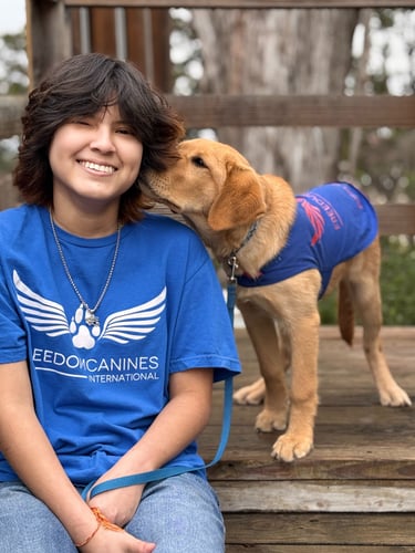 A cute puppy nuzzles his puppy raisers ear while she smiles