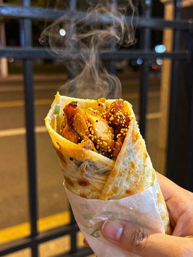 Close-up steaming hot chicken roll held in a student's hand near a dark metal campus gate at night, warm high-contrast street lighting, rich saturated colors