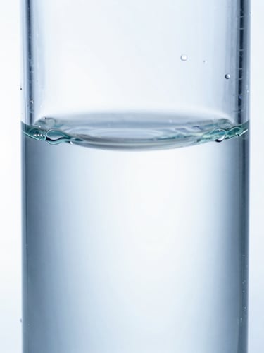 Extreme macro photograph of light refracting through a pure, sterile clear liquid biopolymer in a quartz cuvette, high-key white background, cool blue tones, clinical focus.