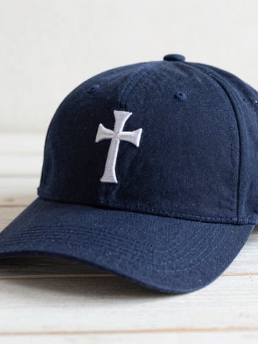 Primer plano detallado de una gorra InVicto con un bordado de fe, sobre una superficie de madera clara, con luz suave de la mañana y sombras sutiles, texturas de tela visibles.