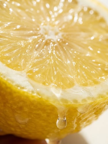 Close-up macro shot of a fresh cut lemon dripping with juice under bright, high-key natural sunlight with sharp shadows, 50mm