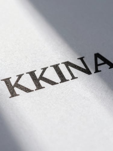 Macro close-up of a printed brand manual with heavy sans-serif typography on textured white paper, sharp sunlight shadow.