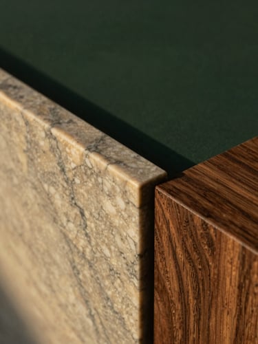 Macro shot of premium architectural materials, vein-cut travertine marble meeting dark walnut wood under soft natural light, minimalist detail.