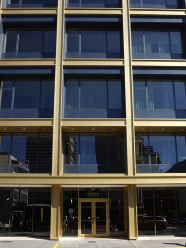 Straight-on architectural shot of a modern Cape Town commercial building with clean lines under bright coastal daylight, deep navy shadows, premium gold trim