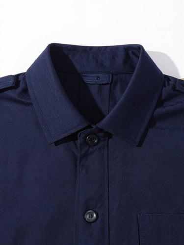 Crisp, high-key studio photograph of a sharp, well-fitting dark navy uniform collar with detailed embroidery stitching, bright natural daylight, 35mm.