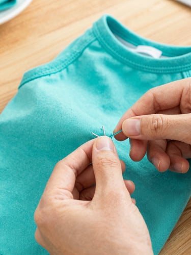 Close-up of artisan hands carefully stitching a bright teal pet shirt on a wooden workshop table, warm natural light, detailed macro shot of handmade finishes