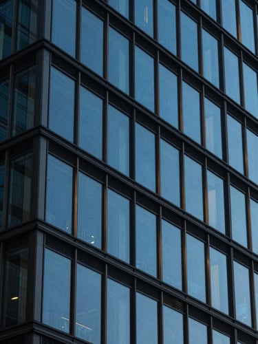 Abstract close-up of a modern glass and steel building facade, geometric lines, cool blue-hour tones, high contrast, 35mm