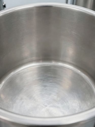 Macro shot of a pristine stainless steel vat interior, bright clean-room lighting, crisp industrial photography, cool metallic tones.