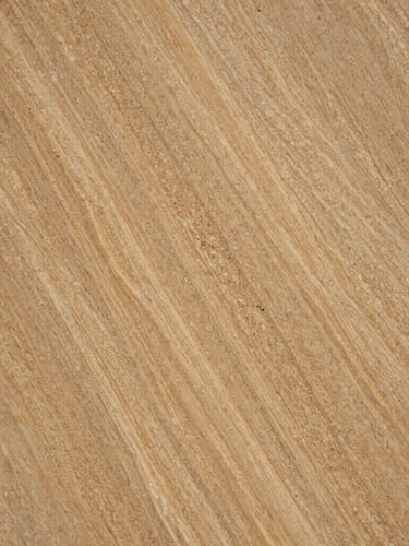 Macro close-up of a premium polished travertine slab, rich warm sand tones, intricate natural cavities and parallel vein patterns catching sharp side-lighting, architectural texture.