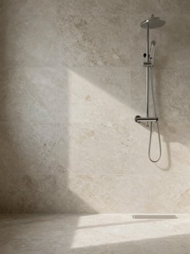 Straight-on architectural elevation of a minimalist bathroom featuring large-format travertine tiles with flawless zero-threshold transitions, soft natural side-light.