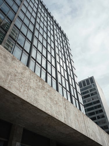 Wide architectural angle of a modern concrete and glass building facade in São Paulo, sharp geometric shadows, cool overcast daylight, negative space.