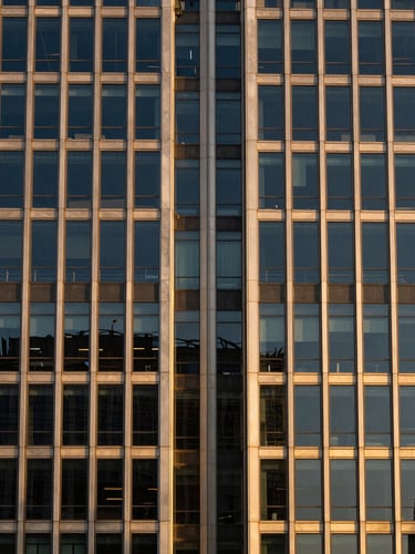 Symmetrical architectural detail of a modern glass and steel skyscraper facade, golden-hour window light, sharp details, 35mm