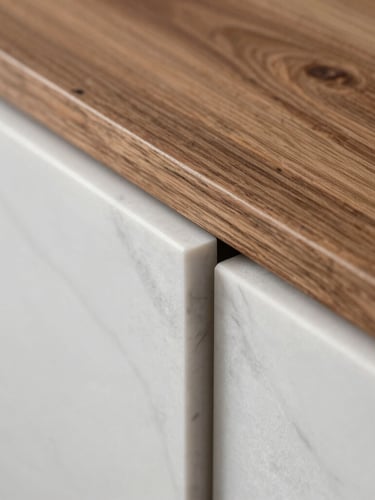Close-up of premium raw materials, smooth white marble meeting textured teak wood under soft side lighting, architectural detail