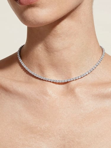 Elegant close-up of a model's collarbone wearing a delicate diamond necklace, soft diffused daylight, clean hydrated skin, high-fashion editorial, 35mm