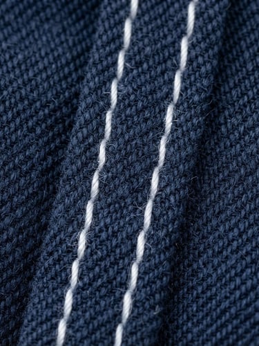 Close-up of a tightly woven, deep navy school uniform fabric, showing reinforced double-stitching, under bright studio lighting, sharp focus on texture, 50mm lens.