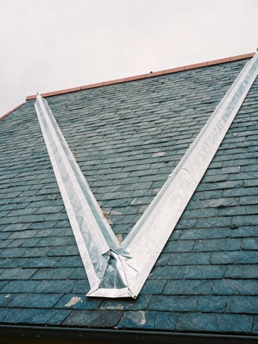 Low-angle documentary shot of a traditional French slate roof with meticulously crafted zinc valleys under a soft overcast sky, sharp details on slate textures, 35mm