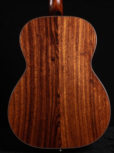 Polished guitar back made of highly figured reclaimed mahogany, catching dramatic studio side-glare, obsidian background