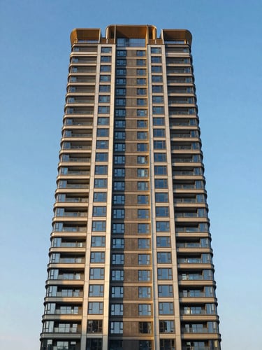 Symmetrical architectural perspective of a modern luxury high-rise tower facade against a clear blue sky, shot at golden hour