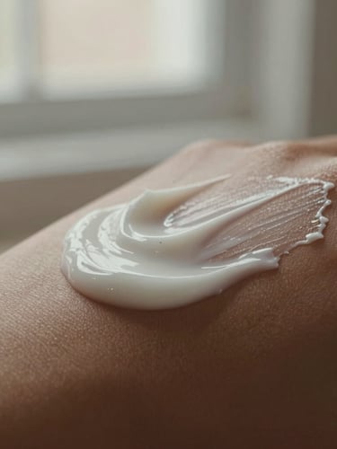 Macro close-up of rich cream lotion being slowly smoothed onto warm skin, soft afternoon window light, earthy cream and taupe tones