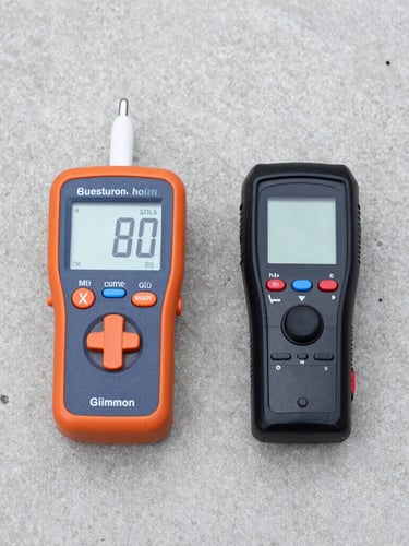 Straight-on orthographic view of a digital moisture meter and thermal camera resting on a clean concrete surface, natural overcast lighting.