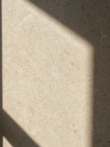 Extreme close-up of un-honed travertine texture, warm afternoon window light, deep shadows, cream and travertine tones, medium format film