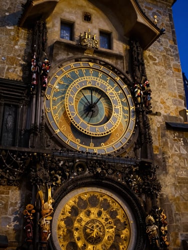 Close-up of the Prague Astronomical Clock golden details illuminated at night, dark blue sky background, dramatic contrast, 35mm lens