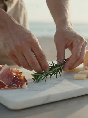 Close-up of hands arranging a sprig of fresh rosemary on a marble slab next to aged prosciutto and artisan cheeses, soft afternoon coastal daylight, shallow depth of field, 35mm