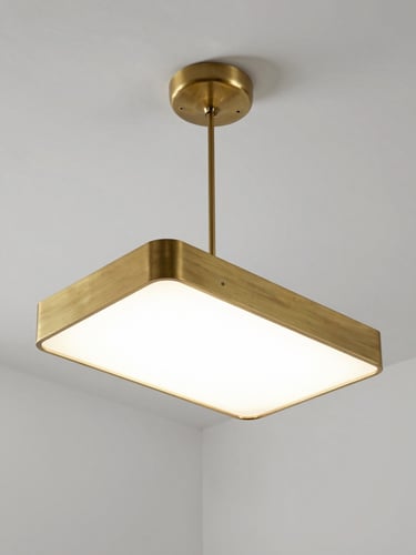 Single large pendant fixture suspended in a stark white architectural void, viewed from below-left at a three-quarter angle, studio strobe lighting rendering every machined edge and matte brass surface with clinical precision, no furniture, no decor, empty white ceiling plane receding into background