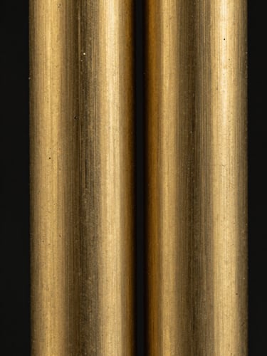 Extreme macro of a brass fixture surface showing brushed grain and patina stages side by side, cool strobe lighting rendering the texture at near-microscopic detail, black background, no context