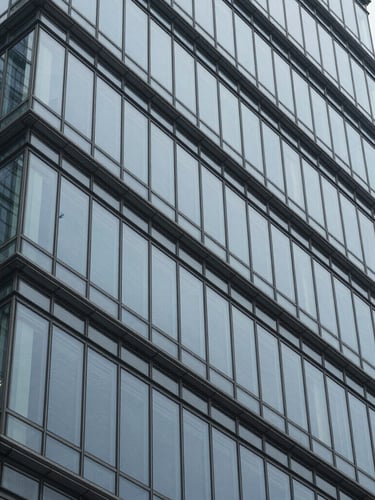 A close-up, abstract macro shot of clean steel and glass structural lines of a modern financial skyscraper, cool overcast daylight, desaturated blue tones