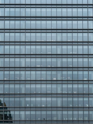 Minimalist architectural detail of a modern steel and glass skyscraper facade, cool overcast daylight, desaturated blue and slate tones, sharp focus