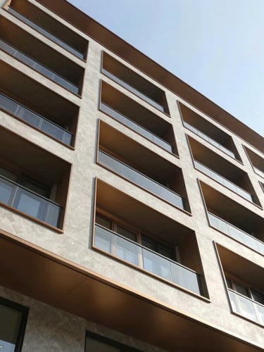 Low-angle architectural photography of a completed modern building facade, sharp geometric concrete lines, bright natural daylight, warm bronze accents