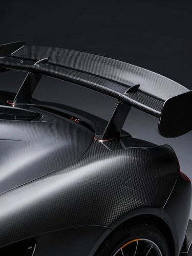 Moody close-up of a carbon fiber aerodynamic wing on a modern supercar, dramatic low-key studio lighting, metallic highlights, sharp 35mm details