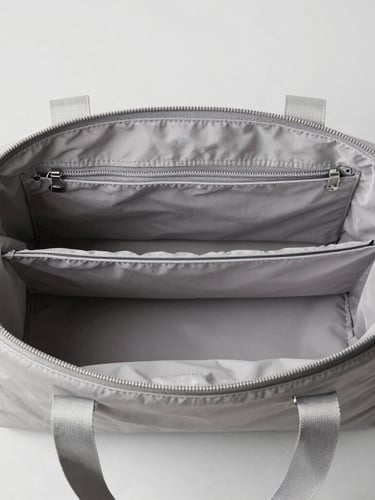 Overhead shot of a minimalist daily carry bag showing structured internal compartments, soft daylight, sharp focus
