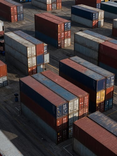 Wide-angle drone perspective of a massive container terminal in Gujarat, geometric stacks of colorful shipping containers, deep charcoal and metallic tones, sharp morning light