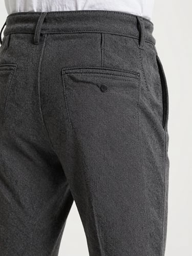 Portrait orientation showing a close-up of charcoal cotton canvas trousers with clean flat-felled seams and technical pocket details.