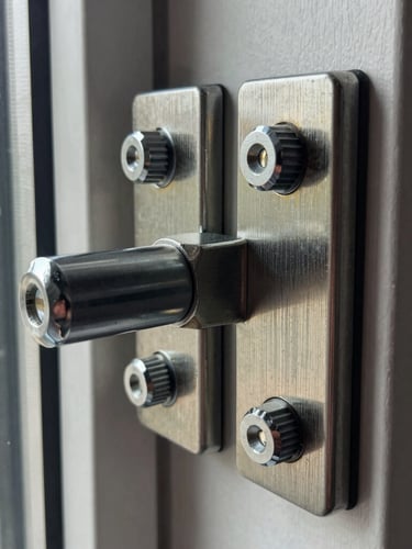 Sharp technical photography of a heavy-duty multi-point security door lock mechanism, natural window daylight reflecting off high-contrast metallic steel bolts, macro lens showing realistic metal textures, 35mm