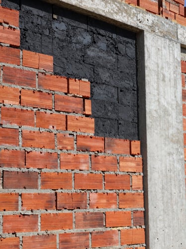 industrial construction photography, hard direct daylight, close-up of exposed brick and concrete walls being restored, high contrast red and black tones, sharp focus, 35mm lens