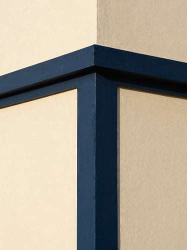 Close-up architectural shot of a perfectly painted modern wall corner, sharp high-contrast line between deep navy and warm cream, natural light, 35mm lens.