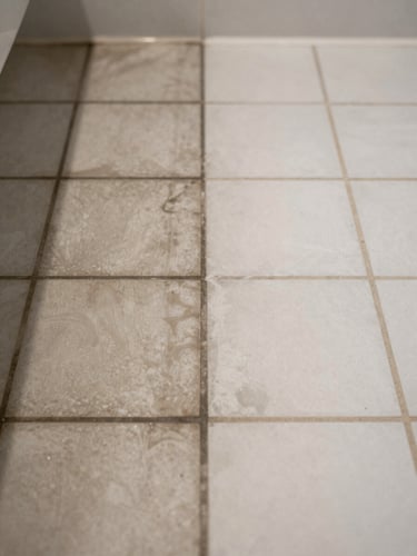 Close-up of a bathroom floor mid-restoration, stained dark grout lines on the left half of the frame, freshly cleaned and recolored white grout lines on the right half, consistent overhead bathroom light, tight crop showing the contrast zone clearly